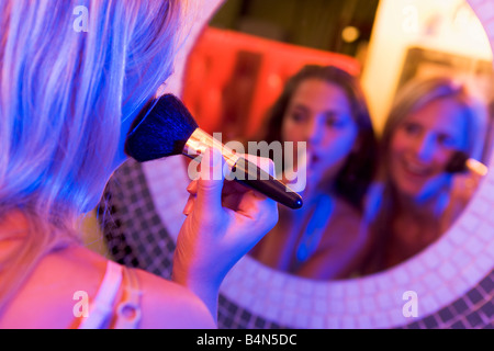 Zwei junge Frauen, die beim Schminken in einem Spiegel Stockfoto