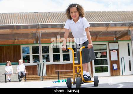 Schüler außerhalb der Schule auf Dreirad Roller Stockfoto