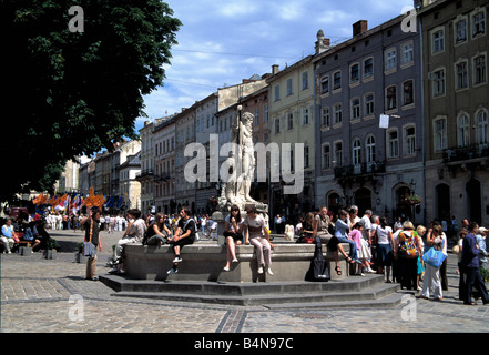 Menschen, die von Neptun-Brunnen in Ploshka Rynok Square auf Krakivska Straße in Lwow, Westukraine Stockfoto