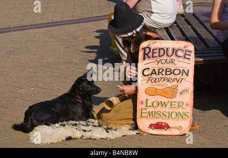 Frau mit Schild anmelden Shopping Centre UK reduzieren YOUR CARBON FOOTPRINT mit weniger Emissionen Stockfoto