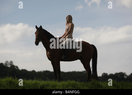 Silhouette einer hübsche blonde Frau auf einem Pferd sitzend Stockfoto