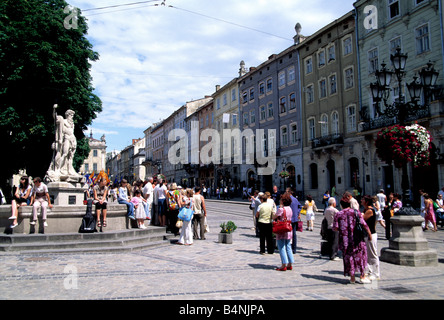 Menschen, die von Neptun-Brunnen in Ploshka Rynok Square auf Krakivska Straße in Lwow, Westukraine Stockfoto