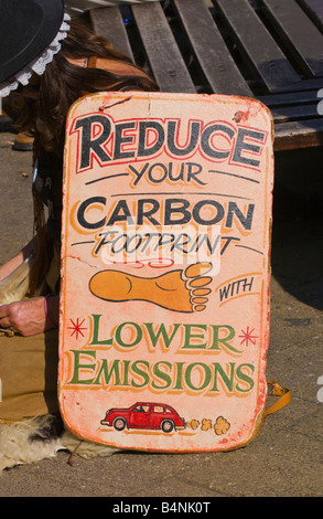 Frau mit Schild anmelden Shopping Centre UK reduzieren YOUR CARBON FOOTPRINT mit weniger Emissionen Stockfoto