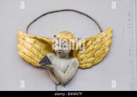 Kleine Engel mit goldenem Haar und Flügeln halten eine Pyramide. Architektonische Details. East London, UK Stockfoto
