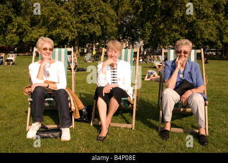 3 ältere Frauen sitzen auf Liegestühlen im Hyde Park, London, UK. Stockfoto