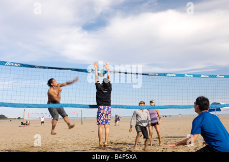Junge Menschen, die am Strand Volleyball spielen Stockfoto