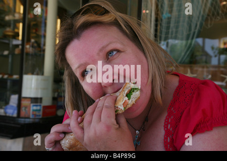 Größere Dame ein großen Sandwich zu essen Stockfoto