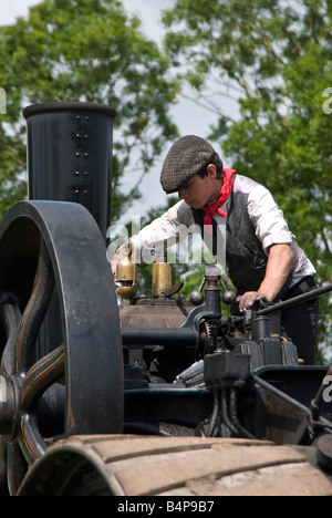 Ein Junge Enthusiasten in zeitgenössischer Kleidung reinigt, schmiert und zeigen einen Dampftraktor bereitet. UK Stockfoto