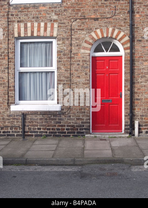 Kleines Reihenhaus mit einer bunt bemalten rote Tür in Middlesbrough England UK Stockfoto