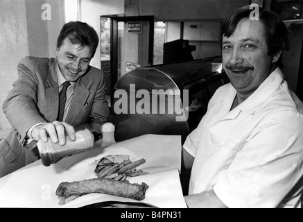 Herr Terry Cutlan in seinem Chip Shop The Coldstream Garw Croesyceiliog dient Kunden Herr Martin Willis mit seinem Dorsch mit einem Gewicht von fünf und eine halbe Unze und kostet 85p plus Chips Dezember 1988 Stockfoto