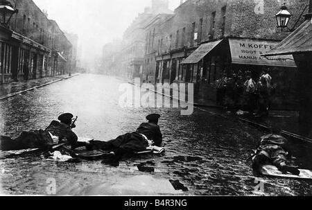 Die Szene aus der Sidney Street Belagerung mit Scots Guards in Gewehr liegend auf dem Kopfsteinpflaster, während Herr Winston Churchill und die Polizei an der Ecke der Straße aus dem Weg zu verirrten Kugeln Kriminalität Seige Polizisten britische Armeesoldaten Januar 1911 1910er Jahre Mirrorpix stehen Feuerstellungen Stockfoto