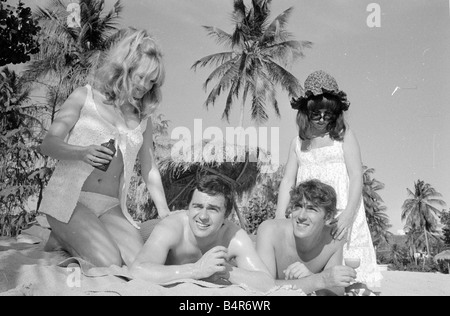 Komiker Schauspieler und Verleger Peter Cook mit seiner Frau Wendy rechts mit Dudley Moore und Suzy Kendall gesehen hier mit Sonnenöl eingerieben in ihren Rücken während eines Urlaubs in Grenada März 1966 Stockfoto