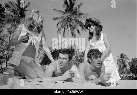 Komiker Schauspieler und Verleger Peter Cook mit seiner Frau Wendy rechts mit Dudley Moore und Suzy Kendall gesehen hier mit Sonnenöl eingerieben in ihren Rücken während eines Urlaubs in Grenada März 1966 Stockfoto