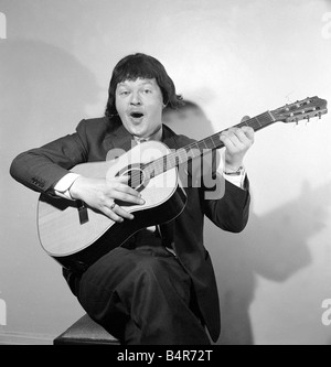 Komiker Benny Hill abgebildet zu Hause das Tragen einer Perücke und spielt Gitarre Mai 1958 Stockfoto