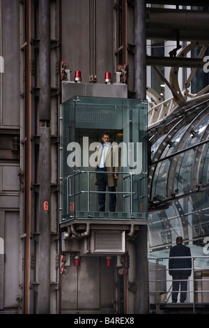 Mann in externen Glasaufzug bei Lloyds Versicherung Gebäude in der City of London, UK. Stockfoto