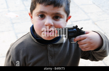 Junge arabische weist eine Spielzeugpistole auf diesen Mund auf dem Markt in der Nähe von Damaskus-Tor in der Jerusalemer Altstadt. Stockfoto