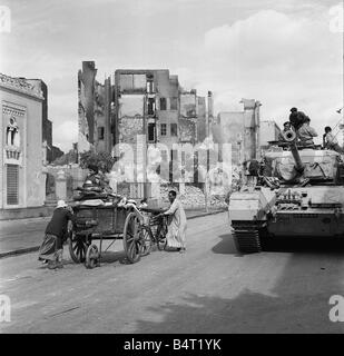 Suez Krise 1956 ägyptische Flüchtlinge ihre Habseligkeiten in einen Warenkorb zu entfernen, wie ein Centurion-Panzer verleiht Unterstützung für Kommando-Truppen, die die Durchführung einer systematischen Suche aller Häuser in Port Said für Arme Stockfoto