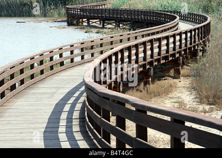 Ein langer, geschwungener Holzsteg auf Stelzen schlängelt sich durch das Schilf eines Küstenlagunenreservats in der Nähe von Cagliari, Sardinien, Italien. Stockfoto
