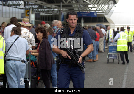 Bewaffnete Polizisten patrouillieren die Schlange der Passagiere warten außen Terminal 4 am Flughafen Heathrow, wo British Airways über 40 Prozent der Flüge nach der Regierung und dem Flughafen Behörden hereingebracht strengere Sicherheitsmaßnahmen nach einer abgebrochenen Bombenanschlag August 2006 abgesagt Stockfoto