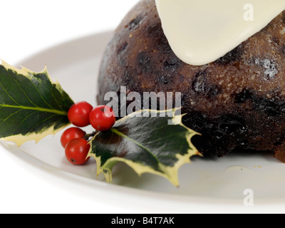 Eine traditionelle Weihnachtspudding mit Holly und Rote Beere traditionellen Dekorationen und gekrönt mit Brandy Sauce auf Teller serviert gegen Weiße Stockfoto