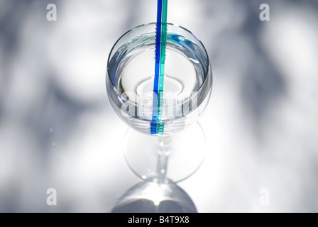 Glas Wein gefüllt mit klarem Wasser und zwei Zahnbürsten erschossen von oben auf schattigen weißen Hintergrund Stockfoto