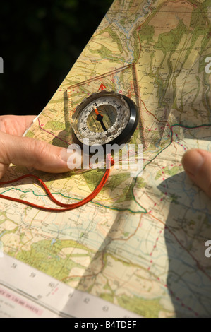 Überprüfen der Wegbeschreibung einer Wanderroute auf einer Papierkarte und einem Kompass aus nächster Nähe Stockfoto
