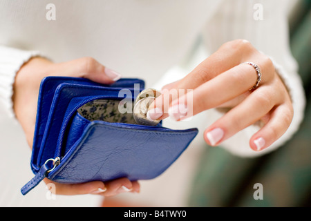 junge Frau, die Münzen im Geldbeutel setzen Stockfoto