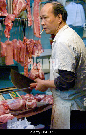 Einem lokalen Metzger ein Fleischerbeil schärfen und Rauchen auf dem Wan Chai nassen Markt in Hong Kong. Stockfoto