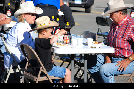 Ein Cowboy und seine Frau essen Pfannkuchen mit ihrem Enkel in einem rotary Club-Pancake-Frühstück Stockfoto