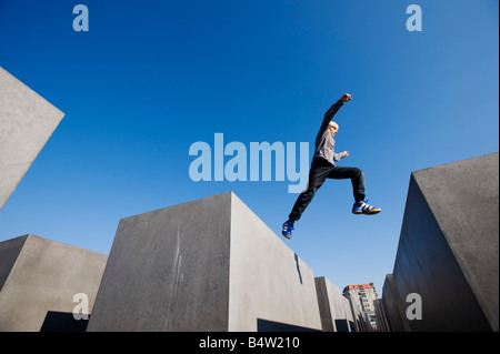 Junge springt zwischen Betonblöcken am Denkmal für die ermordeten Juden Europas im Zentrum Berlins Stockfoto