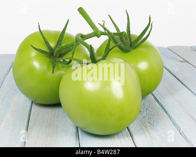 drei unreife Tomaten auf einem Holztisch Stockfoto