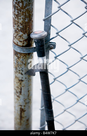 Eine alte Softball-Schläger, lehnte sich gegen einen Maschendrahtzaun. Stockfoto