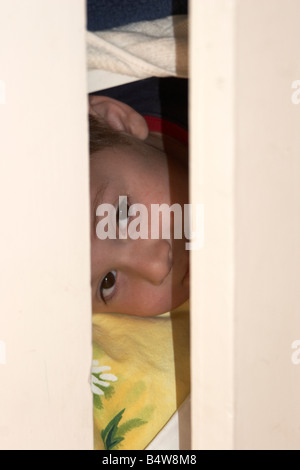 Kleiner junge Kind versteckt in einem Schrank CJWH Stockfoto