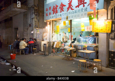 Eine Familie der chinesischen Abendessen außerhalb einer kleinen lokalen Curbside Restaurant am Rande der Temple Street Market. Stockfoto