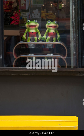 Zwei Spielzeug grüne Frösche im speichern Fenster Stadt urban Stockfoto