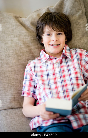 Junge auf einer Couch, mit einem Buch Stockfoto