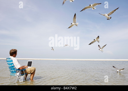 Mann mit Laptop in der Mitte des Wasser Stockfoto