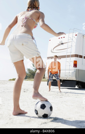Junges Paar Fußball spielen am Strand Stockfoto