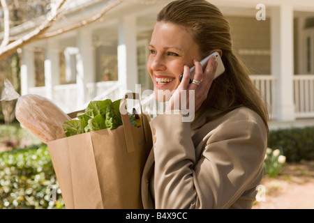 Frau mit Lebensmittel und am Telefon sprechen Stockfoto