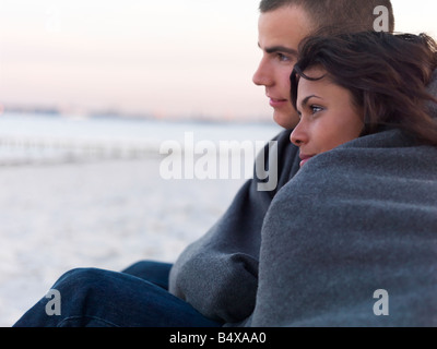 Junges Paar eingewickelt in Decken am Strand Stockfoto