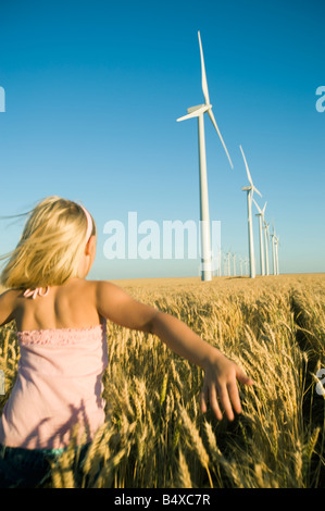 Mädchen läuft durch hohen Weizenfeld am Windpark Stockfoto