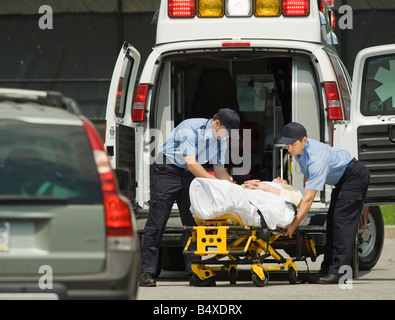 Laden von Patienten in Krankenwagen Sanitäter Stockfoto