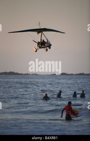 Microlite fliegen über das Meer und die Surfer am Strand von weißen Felsen in Portrush bei Sonnenuntergang Northern ireland Stockfoto