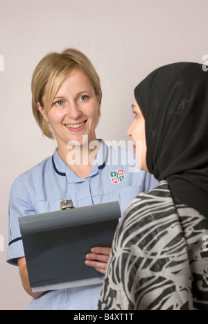 Junge weiße Krankenschwester spricht mit einer asiatischen Frau im Krankenhaus. Stockfoto