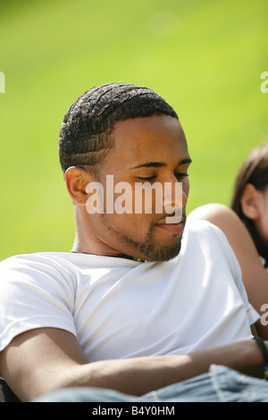 Junger Mann auf dem Rasen mit Freunden entspannen Stockfoto