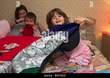 Familie Eröffnung Weihnachtsgeschenke im Bett am Weihnachtsmorgen Stockfoto