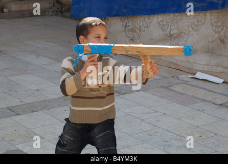 Ein arabischer junge mit einem Stück Holz als eine Spielzeugpistole in einem gepflasterten Innenhof in der Nähe seines Hauses im arabischen Viertel der Jerusalemer Altstadt. Stockfoto