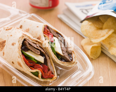 Steak, Käse, rote Paprika und Barbeque-Sauce Tortilla Wrap mit einer Dose Cola und Packung Chips Stockfoto