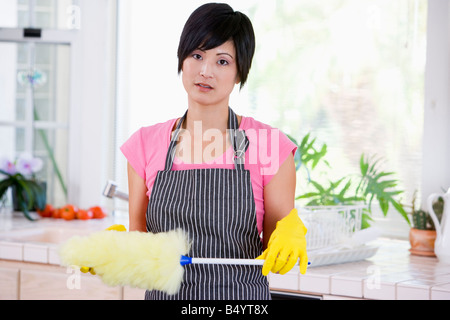 Frau mit Duster und tragen Gummihandschuhe, die nicht auf der Suche beeindruckt Stockfoto