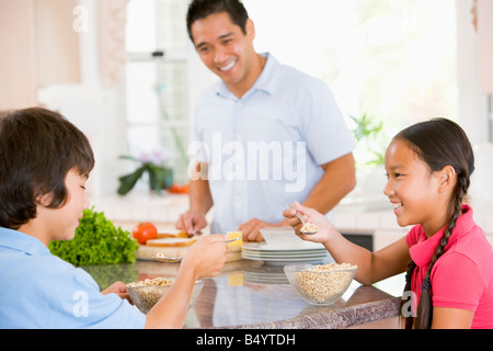 Kinder frühstücken, während Papa Essen bereitet Stockfoto